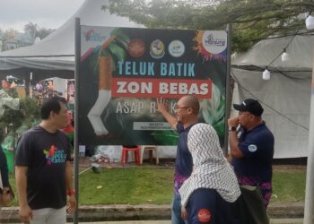 LOH Sze Yee (tiga dari kiri) mendengar penerangan mengenai peraturan larangan merokok di pantai Teluk Batik daripada Syamsul Hazeman Md. Salleh pada program di Lumut hari ini. - UTUSAN