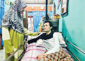 NORIPAH Abdul Majid tabah menjaga Mohd. Munir sejak 15 tahun lalu yang lumpuh akibat kemalangan, di Rembau, Negeri Sembilan. 
– UTUSAN/NOR AINNA HAMZAH