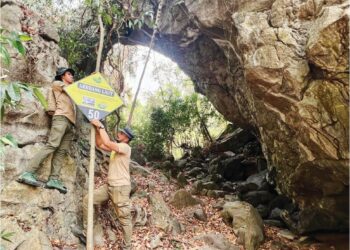 SYAMIL Abd. Rahman (kiri) dan Ahmad Fahmi Mohd. Radzi membetulkan papan tanda cadangan bagi formasi batuan 
di gerbang laut dipercayai berusia jutaan tahun yang ditemui di Bukit Besi Hangit, Kangar. – UTUSAN/ASYRAF MUHAMMAD