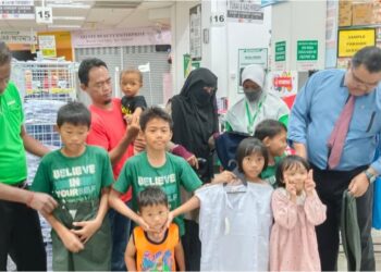 MAS IMRAN Adam  (kanan) membantu memilihkan baju untuk anak-anak Mohd. Hassan dan Norain 
di Pasaraya Econsave Permas Jaya, Johor Bahru.