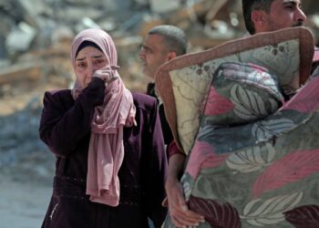 SEORANG wanita menyapu air mata ketika melalui runtuhan bangunan kediaman di bandar Hamad di barat Khan Younis.-AFP