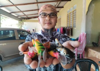 AHMAD Sharul Mohamed menunjukkan sebahagian koleksi umpan tiruan yang dibuat daripada kayu pulai di Kampung Kayu Kelat 6, Kuala Besut, semalam. - UTUSAN/WAN ZURATIKAH IFFAH WAN ZULKIFLI