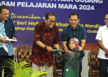 Datuk Seri Mohamed Khaled Nordin menyampaikan  bantuan persekolahan kepada salah seorang kanak-kanak pada Program Bantuan Khas Persekolahan Yayasan Pelajaran Mara anjuran UMNO bahagian Pasir Gudang dan Yayasan Pelajaran Mara 2024 di Dewan Muafakat Taman Bukit Dahlia, Pasir Gudang disini. UTUSAN/RAJA JAAFAR ALI