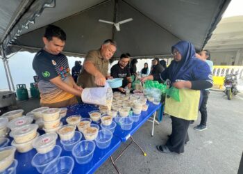 ROZABIL Abd Rahman  bersama mahasiswa menyediakan bubur lambuk untuk diedarkan buat orang ramai sekitar kawasan Arau, Perlis semalam. -UTUSAN/ASYRAF MUHAMMAD