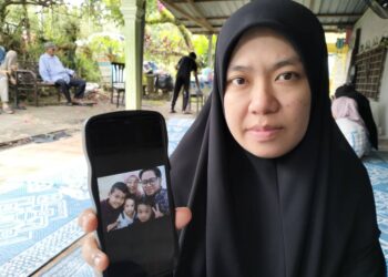 UMI Salwa Ab. Hamid menunjukkan gambar keluarga adiknya yang maut dalam nahas jalan raya di Kilometer 76.5, Jalan Kota Bharu-Gua Musang dekat Kampung Pahi, Kuala Krai, Kelantan semalam. - UTUSAN