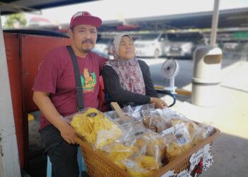MOHAMAD Fackri Mohamad Diah bersama isterinya, Maizura gigih mencari rezeki menjual kerepek ketika ditemui di Nilai, baru-baru ini. - UTUSAN/NUR SHARIEZA ISMAIL.