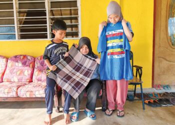 NORHASYIMA Mohd. Yatim bersama dua anaknya, Nur Aishah Natasha dan Muhammad Yusuff Danial memegang pakaian yang sering dipakai oleh Allahyarham Abd. Shukur Abdullah Suhaimin.