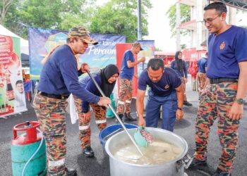 Anggota bomba Putrajaya mengacau bubur lambuk pada program Kongsi Berkat Bubur Lambuk anjuran Media Mulia bersama Mahsuri Food di Ibu Pejabat JBPM Putrajaya, kelmarin. - FARIZ RUSADIO