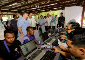 Amir Hamzah Azizan (berdiri, dua dari kiri)  meninjau kaunter Bank Simpanan Nasional  dalam Program Rintis Penunaian Sumbangan Tunai Rahmah (STR) 2024 Bagi Masyarakat Orang Asli Di Daerah Batang Padang, Tapah, Perak di Dewan Jelutong Hutan Lipur, Kuala Woh, Tapah semalam.