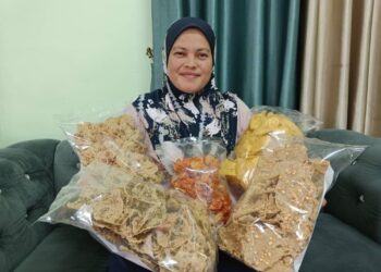 JULIANI Ahmad  menunjukkan kerepek pisang dan rempeyek yang dibuatnya di Kampung Parit Jawa, Sanglang, Pontian, Johor.