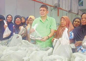 DR. GARY Ko bersama beberapa penerima program sumbangan makanan laut sempena Ramadan di Taman Mount Austin, Johor Bahru, semalam.
