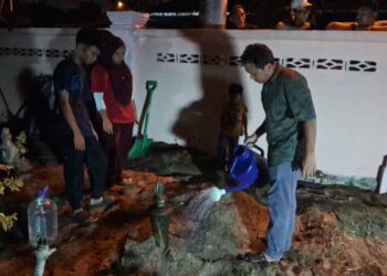AHLI keluarga Muhammad Danish Mikaill Abdullah menyiram pusaranya selepas jenazah selamat dikebumikan di Tanah Perkuburan Islam Syed Yahya, Dungun malam tadi. - UTUSAN/NIK NUR IZZATUL HAZWANI NIK ADNAN