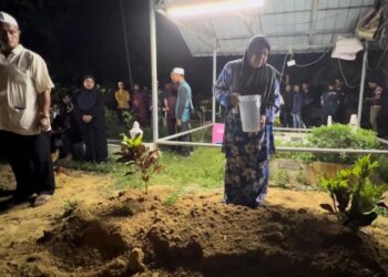 WAN Hussin Wan Ishak (kiri) memerhati isterinya, Hamsah Omar menyiram pusara 
Wan Muhammad Haikal di Tanah Perkuburam Islam Kampung  Alor Selising, Jertih, Besut, malam ini.