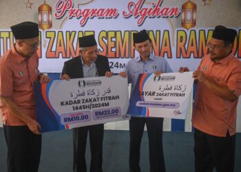 SHAIKH Harun Shaikh Ismail (dua dari kiri) menunjukkan kadar bayaran zakat fitrah di Terengganu pada tahun ini selepas Program Agihan Bantuan Zakat Sempena Ramadan di Kuala Terengganu, hari ini. - UTUSAN/PUQTRA HAIRRY ROSLI