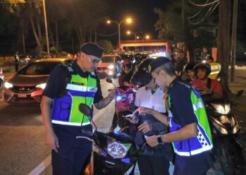ZULKARNAIN Yasin (kiri) bersama anggotanya memeriksa kenderaan dalam Operasi Bersepadu di Jalan Sultan Mahmud dekat Padang Negara, Kuala Terengganu, malam tadi.- UTUSAN/PUQTRA HAIRRY ROSLI
