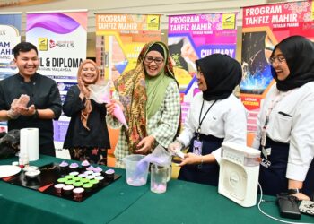 SABARIAH Saidan (tengah) menunjukkan kemahirannya membuat kek cawan di sebuah gerai pameran Pasar Sera di Kompleks Yayasan Pahang di Kuantan, Pahang. - UTUSAN/SHAIKH AHMAD RAZIF