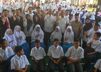 SHAFRUDDIN Ali Hussin (berdiri, lima kiri) bergambar bersama pelajar pada hari pertama sesi baharu persekolahan di SMK Serada, Kuala Terengganu, semalam. - UTUSAN/PUQTRA HAIRRY ROSLI