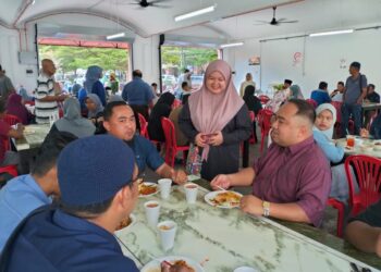 PENYELIA restoran NDAT Cawangan Bandar, Siti Aishah Mohd. Alkamal (berdiri) melayan pelanggan sempena pemberian nasi dagang percuma di Kuala Terengganu, hari ini. - UTUSAN/KAMALIZA KAMARUDDIN