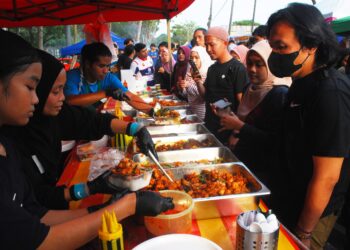 ROSE AIDA Mohd. Nor (depan) sedang membungkus ayam goreng kunyit di Bazar Ramadan Taman Cempaka, Melaka. - UTUSAN/AMRAN MULUP