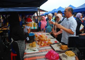 NGWE Hee Sem (kanan) dan Ruzita Mustaffa (dua dari kanan) menyantuni peniaga ketika Op Ramadan di Bazar Ramadan Alor Gajah, Melaka. - UTUSAN/AMRAN MULUP