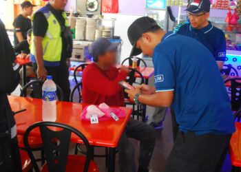 PENGUAT kuasa JAIM mengambil butiran seorang lelaki yang ditahan kerana membeli minuman di sebuah restoran di Ayer Keroh, Melaka. - UTUSAN/AMRAN MULUP