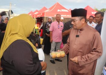 AMIZAR Abu Adam menyumbang juadah berbuka puasa kepada pengunjung di Bazar Ramadan Felda Sungai Koyan di Lipis, Pahang. - FOTO/SALEHUDIN MAT RASAD