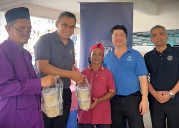 ABDUL Rahman Ahmad (dua dari kiri) mengagihkan bungkusan bubur lambuk kepada penduduk menerusi Program Agihan Bubur Lambuk di Flat Seri Seroja, Taman Tasik Jaya, Seremban hari ini.-UTUSAN/NUR SHARIEZA ISMAIL.