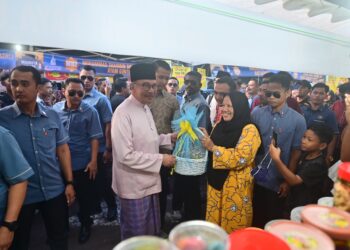ANWAR Ibrahim (kiri) menerima sumbangan kuih raya daripada peniaga bazar di Bazar Ramadan Mahkota Square di Kuantan, Pahang. - FOTO/SHAIKH AHMAD RAZIF