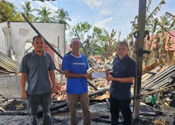 PENGERUSI Biro Sosial dan Kemasyarakatan Gabungan Felda Wilayah Jengka, Razak Daud (kanan) menyampaikan sumbangan wang tunai kepada Mohd. Isa Md. Noor di Felda Jengka 14 di Maran, Pahang.