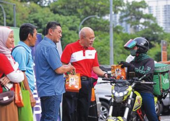 Mohd. Roslan Mahayudin (empat dari kiri) menyerahkan bubur lambuk kepada orang ramai di sekitar Projek Perumahan Rakyat (PPR) Seri Semarak, Kuala Lumpur, kelmarin. – UTUSAN/ M. FIRDAUS M. JOHARI