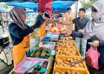 ERYANI Hussin (kiri) melayan pelanggan digerai jualannya di Bazar  Ramadan di Stadium Mini di Pontian, Johor. - UTUSAN/MUHAMMAD ZIKRI