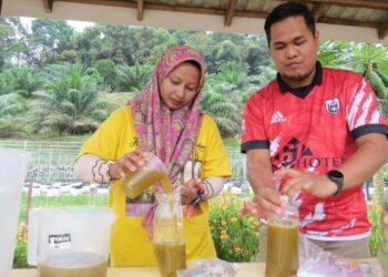AHMAD Fakhrurrazi Che Daud (kanan) membungkus air tebu untuk dijual kepada penduduk di Kampung Lepan Jaya, Gua Musang, Kelantan. – UTUSAN/AIMUNI TUAN LAH
