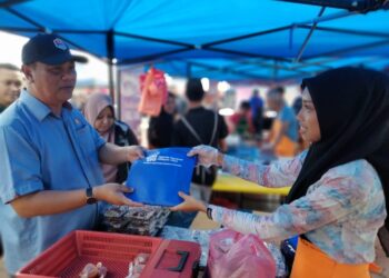 PONTIAN -ABD. Razak Ab. Khalid ( kiri ) menyerahkan kit kebersihan kepada peniaga ketika membuat pemantauan di Bazar Ramdan Stadium Mini Pontian, di Pontian, Johor. KOSMO/UTUSAN/MUHAMMAD ZIKRI