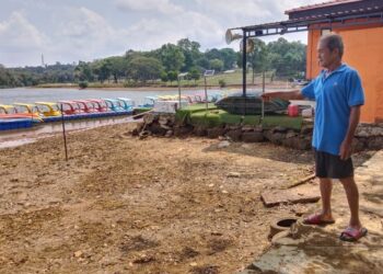 MOHD. RASHID Abd. Samat menunjukkan keadaan paras air Tasik Ayer Keroh, Melaka yang semakin kering. – UTUSAN/MUHAMMAD SHAHIZAM TAZALI