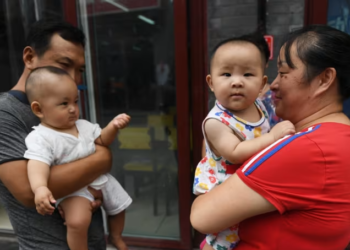 SEORANG lelaki dan wanita memegang bayi di sebuah lorong di Beijing,China pada 1 Ogos 2017.-AFP