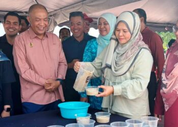 SALBIAH Mohamed (dua dari kiri) memasukkan bubur lambuk ke dalam bekas untuk diagihkan kepada orang ramai pada program Bubur Lambuk Mega 2024 di Bulatan Amanjaya Meru Raya, Ipoh, hari ini. - UTUSAN/LIYANA RAMLI