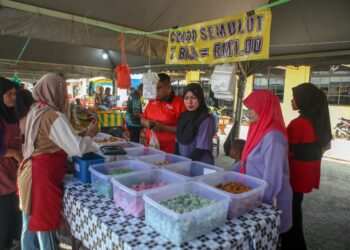 PENGUNJUNG tidak melepaskan peluang membeli pelbagai jenis kuih-muih di gerai Roslina Saad di Felda Lubuk Merbau, Kuala Nerang, Kedah. – UTUSAN/ SHAHIR NOORDIN