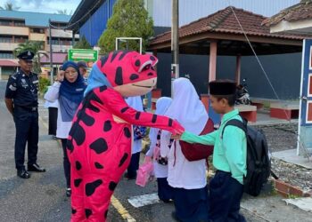 SITI FATIMAH Alip (dua dari kiri) bersama-sama maskot katak menyambut kedatangan murid-murid SK Tengku Mahmood Iskandar (2) pada hari pertama sesi persekolahan di Pontian, semalam.