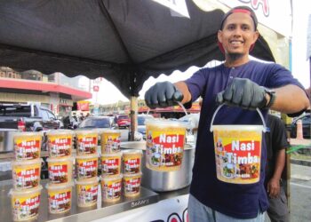 MOHD. Hafifi Mohd. Tajudin menunjukkan nasi timba yang dijualnya di bazar Ramadan di Pekan Baling. – UTUSAN/NORLIA RAMLI