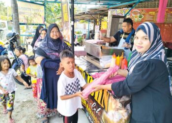 NURUL Mahirran Zulkifily (kanan) memberi roti John percuma kepada golongan asnaf di gerainya di Kampung Semat Jal, Wakaf Bharu, Tumpat, Kelantan. – UTUSAN/ROHANA ISMAIL