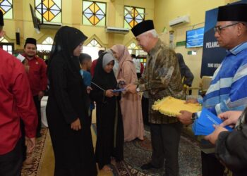 TENGKU Mohamad Rizam Tengku Abdul Aziz (kanan) menyampaikan bantuan awal persekolahan di Pendek, Kota Bharu, Kelantan hari ini.- UTUSAN/ ROSLIZA MOHAMED