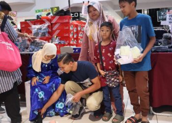 MOHD Sofian Ramli (tengah) membantu anak-anaknya mencari pakaian serta kelengkapan sekolah di sebuah pasar raya di George Town, Pulau Pinang.-UTUSAN/IQBAL HAMDAN