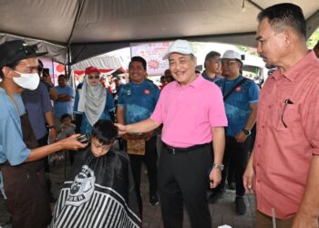 HAJIJI Noor (dua kanan) melawat gerai gunting rambut percuma yang disediakan sempena Mini Karnival Gagasan Rakyat di Kota Kinabalu hari ini