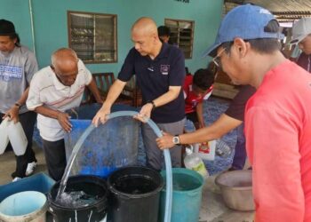 ARMIZAN Mohd. Ali (dua kanan) membantu mengisi air yang dihantar kepada penduduk Kampung Kuala, Papar, Sabah.