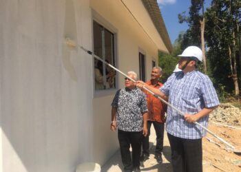 HUSAM Musa (kanan) mengecat sebuah rumah Rumah Mesra Rakyat dengan menggunakan cat insulasi panas ketika Lawatan Kerja ke Tapak Pembinaan RMR di Kampung Tukor, Peringat, Kelantan. UTUSAN/ROSMIZAN RESDI