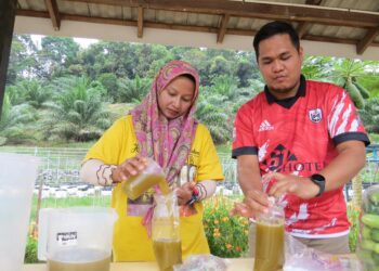 AHMAD Fakhrurrazi Che Daud (kanan) membungkus air tebu untuk dijual kepada penduduk di Kampung Lepan Jaya, Gua Musang, Kelantan.UTUSAN/AIMUNI TUAN LAH.