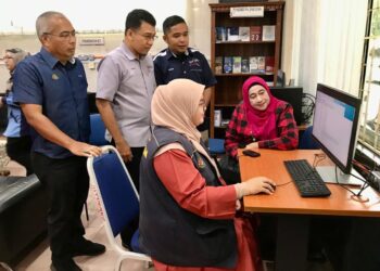 MUHD. Nor Aswadi Md. Nor (tengah) sambil diperhatikan Presiden Kemudi, Muhammad Yatimin Abdullah (kanan) melihat seorang pengamal media mendaftar PADU di Pejabat Penerangan Daerah Kota Bharu hari ini.-UTUSAN/ ROSLIZA MOHAMED