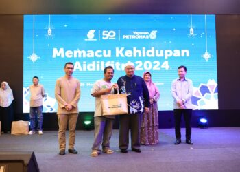 MOHAMAD Fadzli Hassan (tiga kiri) menyampaikan sumbangan kepada salah seorang penerima pada Program Memacu Kehidupan: Hari Raya Aidilfitri anjuran Yayasan Petronas, Kota Bharu, Kelantan-UTUSAN/KAMARUL BISMI KAMARUZAMAN.