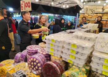 NORENA Jaafar meninjau harga kuih raya yang dijual peniaga ketika Op Samar di Bazar Aidilfitri MITC, Ayer Keroh, Melaka. - UTUSAN/AMRAN MULUP
