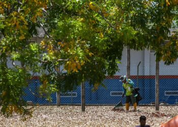 SEORANG pekerja pembersihan menyapu  daun-daun kering yang gugur akibat cuaca terlalu panas di Pokok Sena. -UTUSAN/SHAHIR NOORDIN